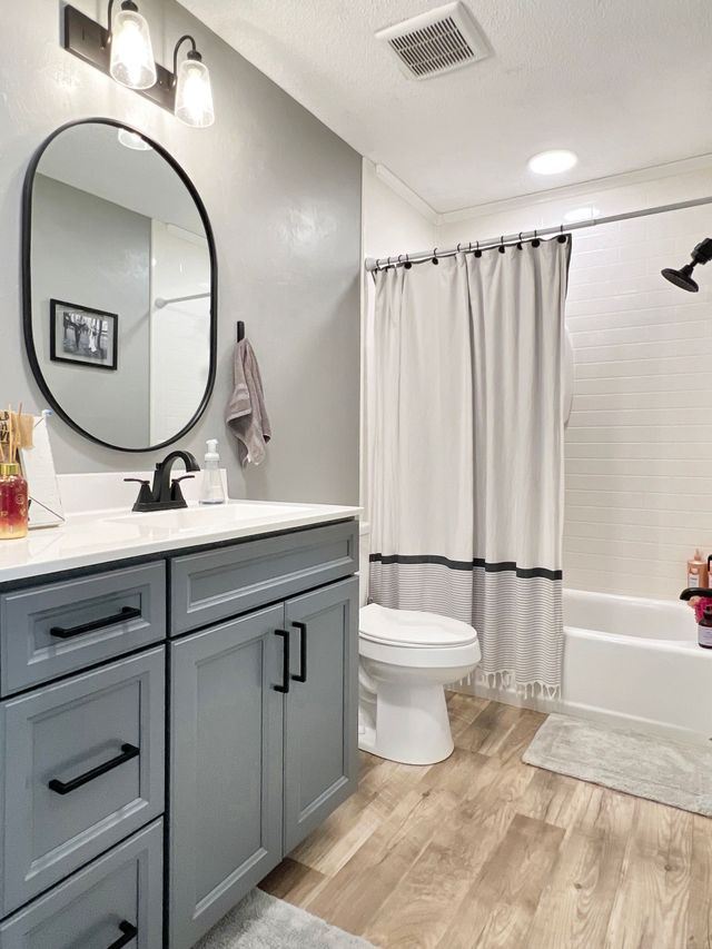A bathroom with a toilet , sink , mirror and bathtub.