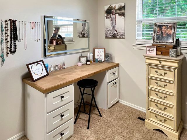 A bedroom with a vanity , dresser , mirror and stools.