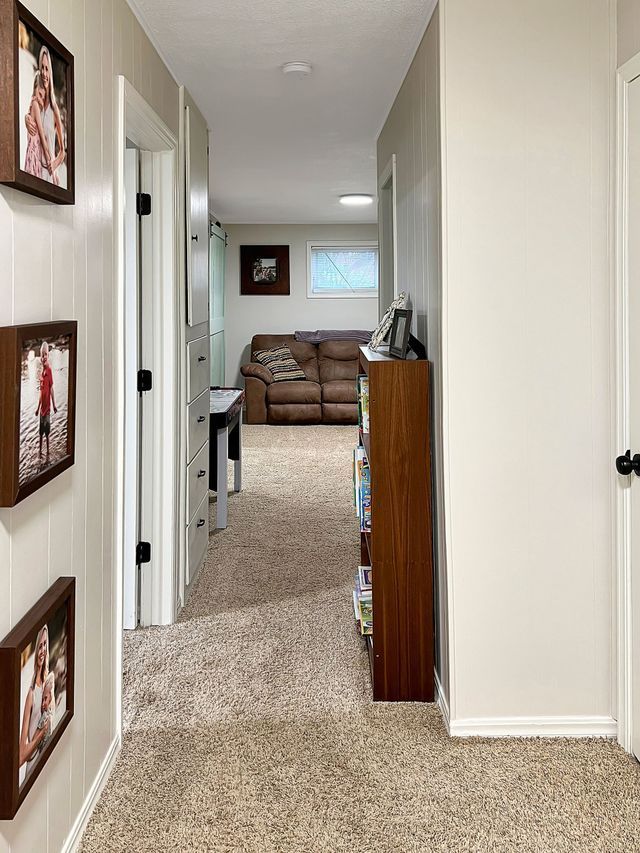 A hallway leading to a living room with pictures on the wall