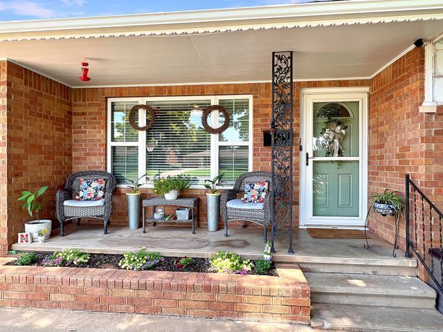 A brick house with a porch and chairs in front of it.
