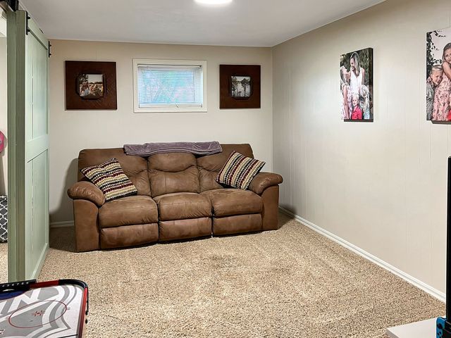 A living room with a brown couch and pictures on the wall.