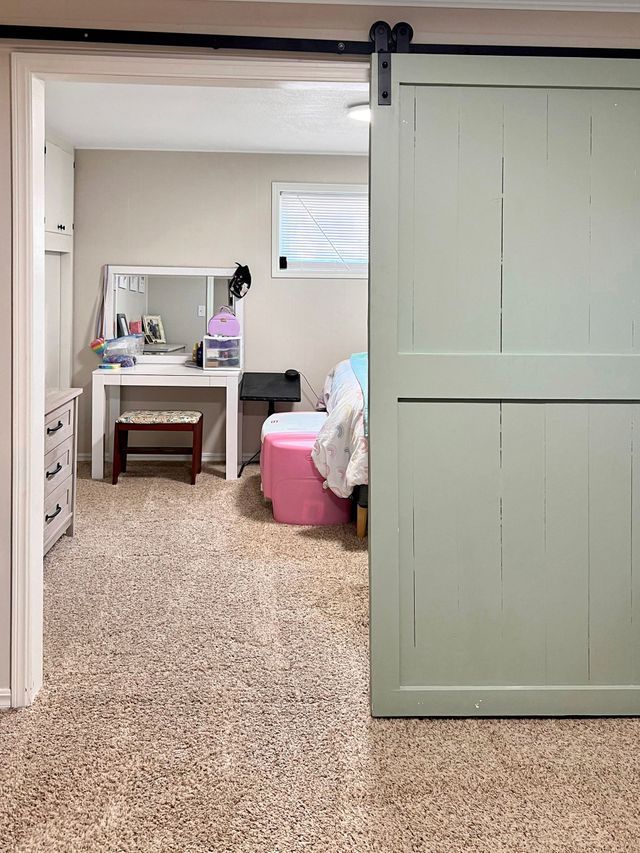 A bedroom with a sliding barn door and a vanity.