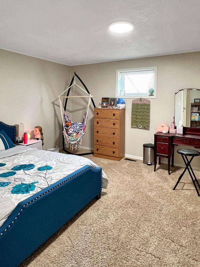 A bedroom with a bed , dresser , mirror and chair.