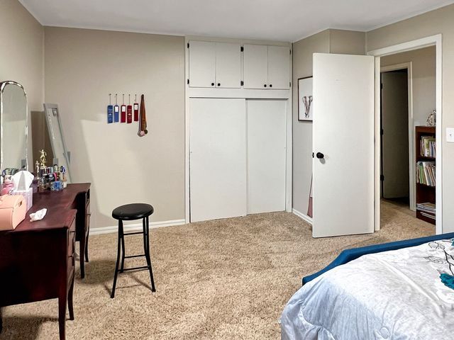 A bedroom with a bed , dresser , mirror and stools.