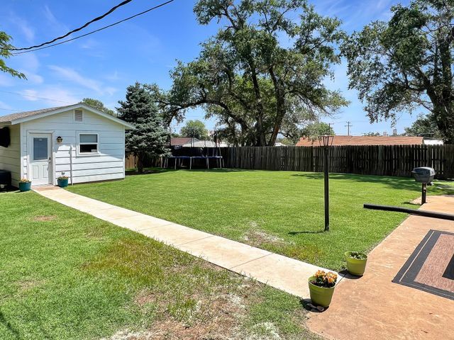 A backyard with a white house and a basketball hoop