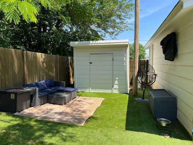 A backyard with a shed a couch and a fan