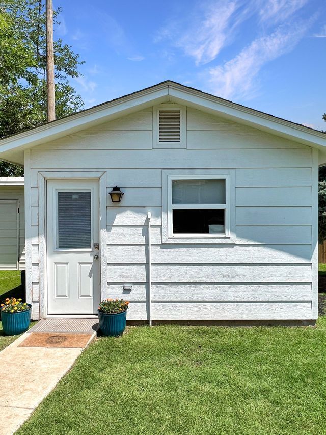 A small white house with a blue potted plant in front of it.