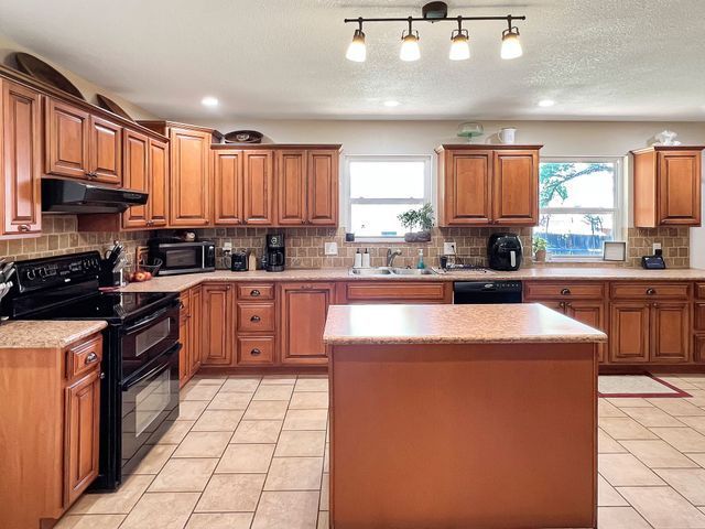 A kitchen with wooden cabinets and a large island in the middle