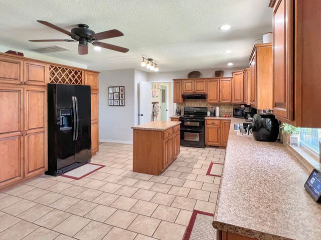 A kitchen with a black refrigerator and a ceiling fan