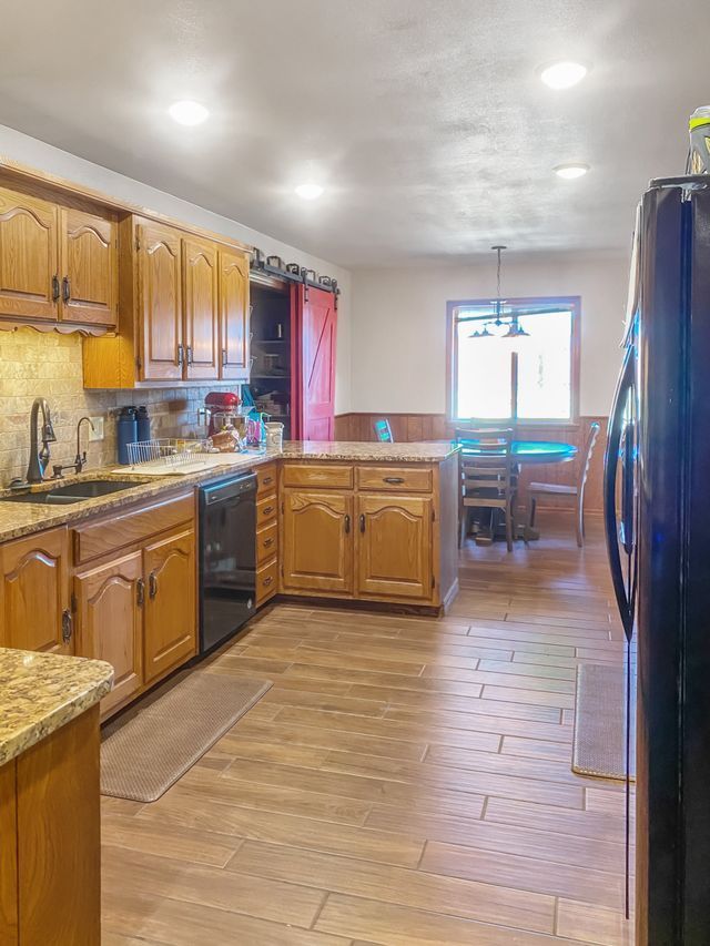 A kitchen with wooden cabinets and a black refrigerator.