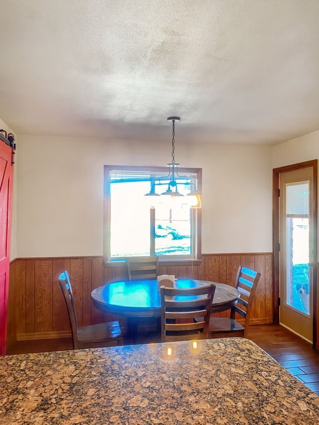 A dining room with a table and chairs and a window.
