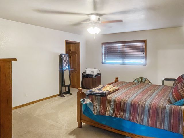 A bedroom with a bed , dresser , mirror and ceiling fan.