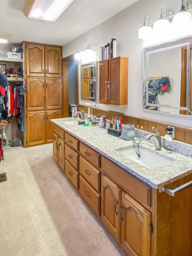 A bathroom with two sinks , two mirrors , and wooden cabinets.