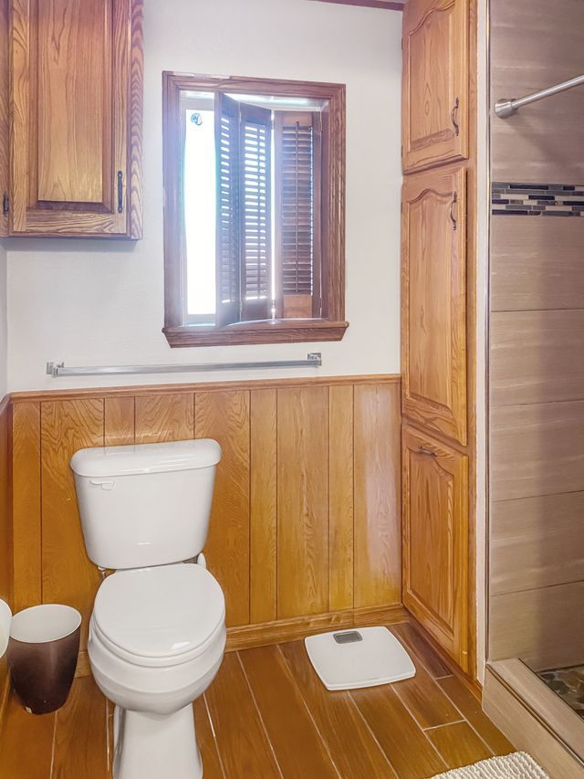 A bathroom with a toilet a scale and a window