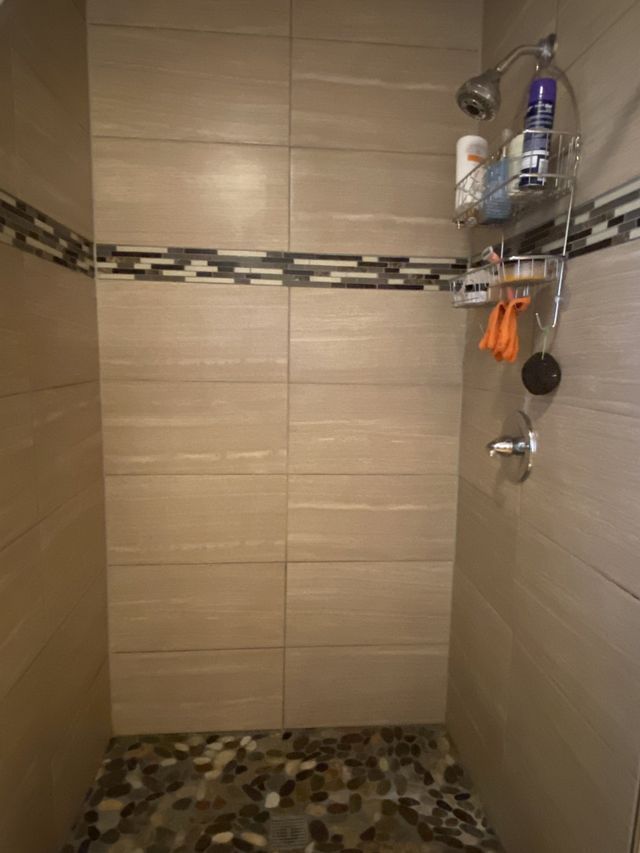 A walk in shower with a tiled floor and a shower head.