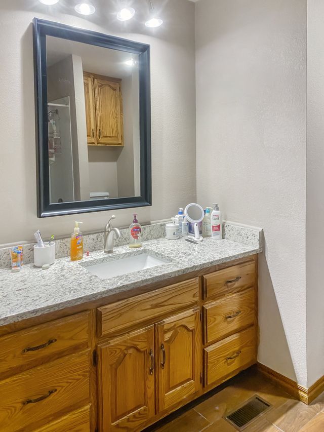 A bathroom with a sink , mirror and cabinets.