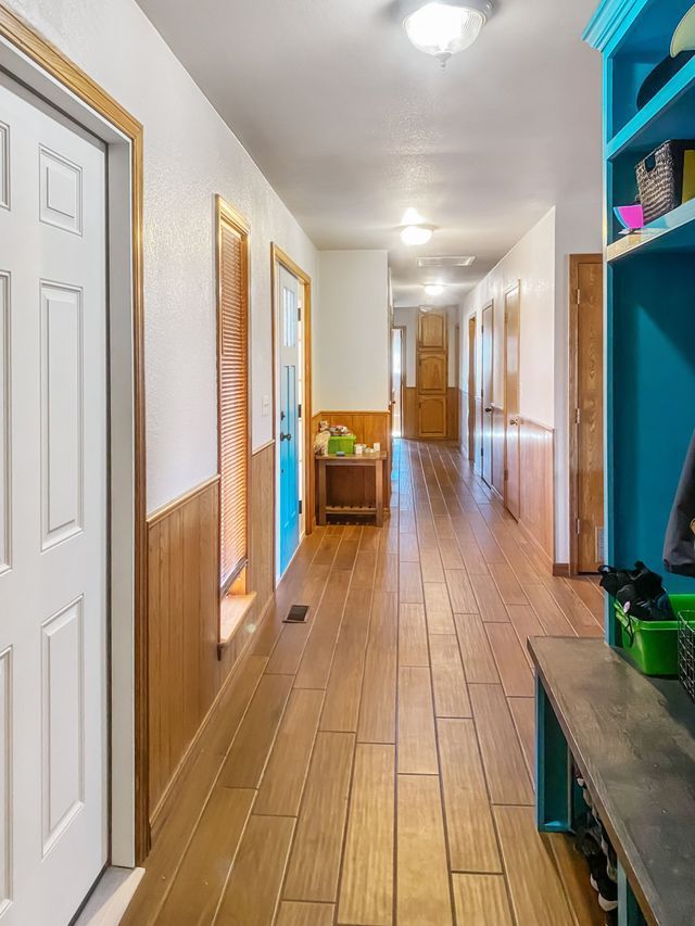 A hallway in a house with wooden floors and a blue cabinet.