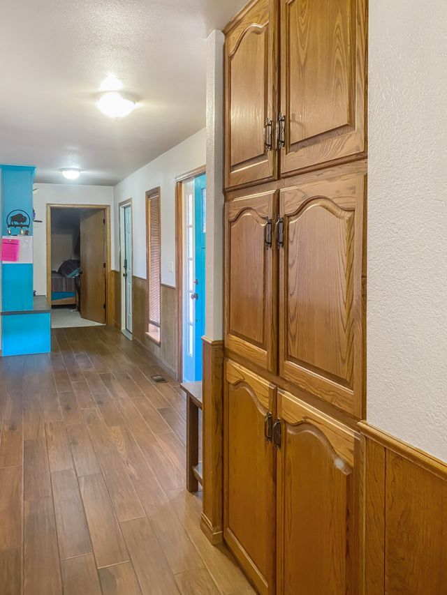 A hallway with wooden cabinets and hardwood floors in a house.