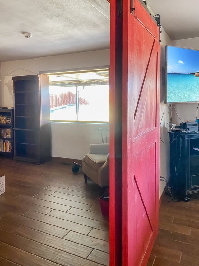 A red sliding barn door is open to a living room.