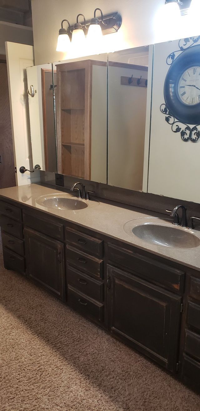 A bathroom with two sinks and a clock on the wall.