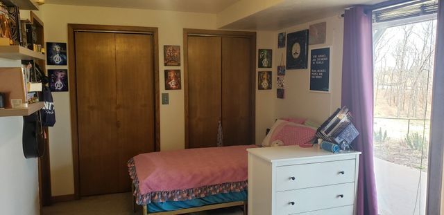 A bedroom with a bed , dresser , and closet.