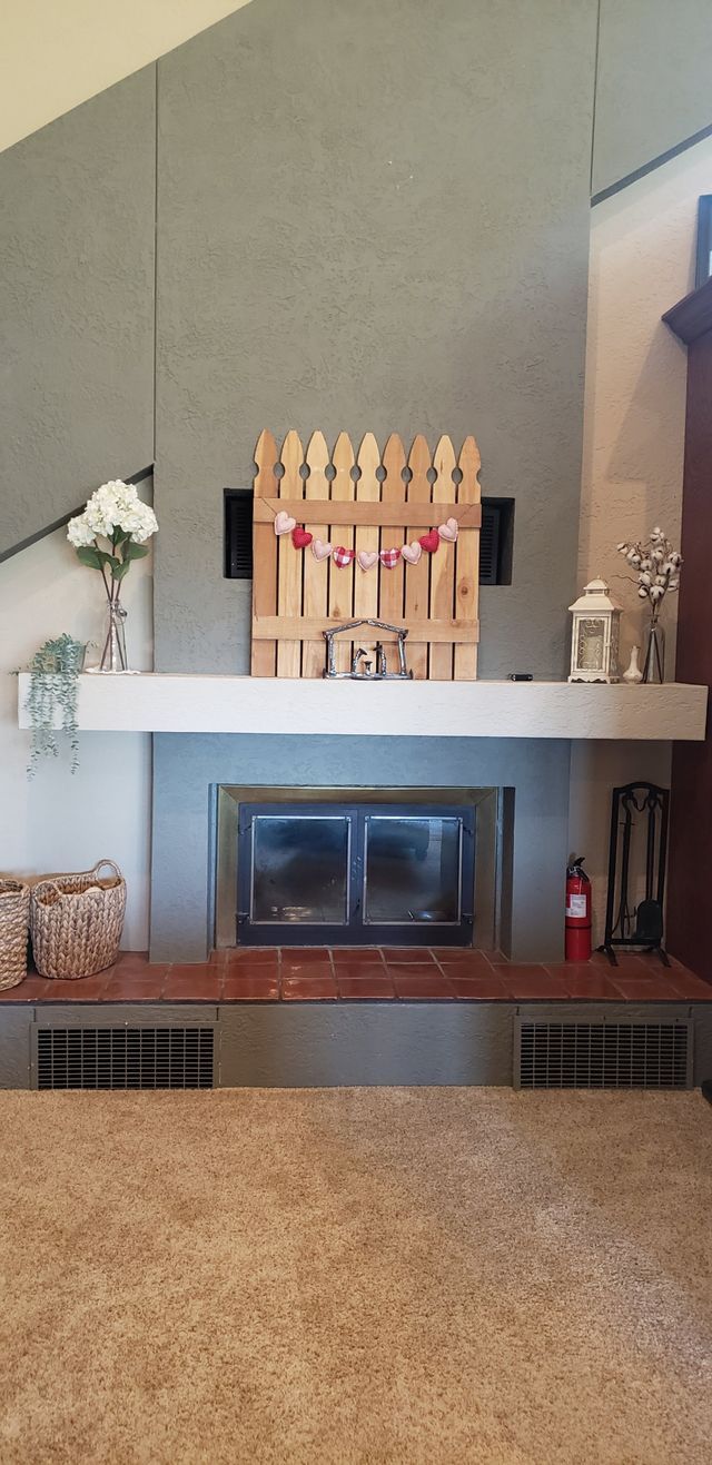 A living room with a fireplace and a wooden fence on the mantle.