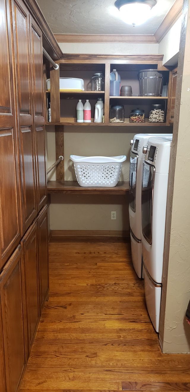 A laundry room with a washer and dryer and a basket on the shelf.