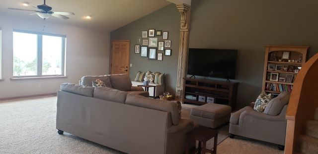 A living room with a couch , chairs , and a television.