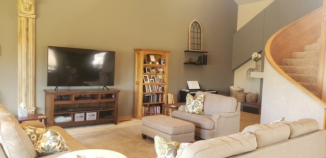 A living room with a couch , chair , television and stairs.