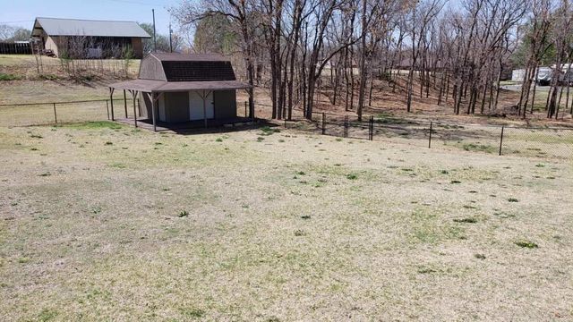 An aerial view of a small house in the middle of a grassy field.