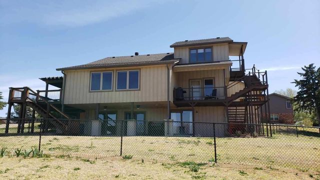 A large house with stairs leading up to the second floor is sitting in the middle of a grassy field.