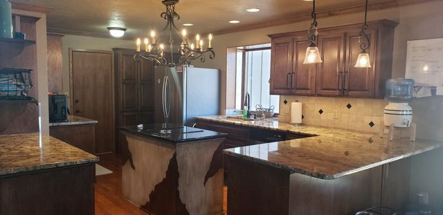 A kitchen with granite counter tops and a chandelier hanging from the ceiling.