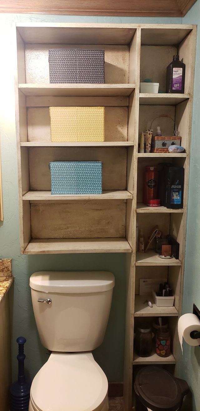 A bathroom with a toilet and shelves above it.
