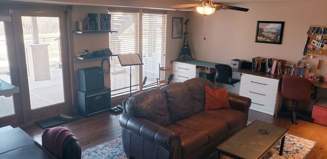 A living room with a couch , table , chairs and a ceiling fan.
