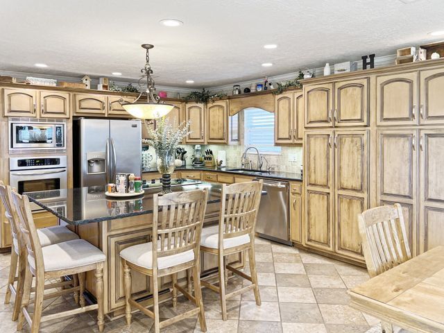 A kitchen with wooden cabinets , stainless steel appliances , a table and chairs.