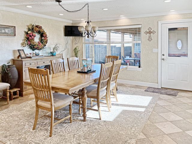 A dining room with a table and chairs and a cross on the wall.