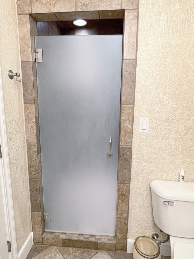 A bathroom with a toilet and a glass shower door.