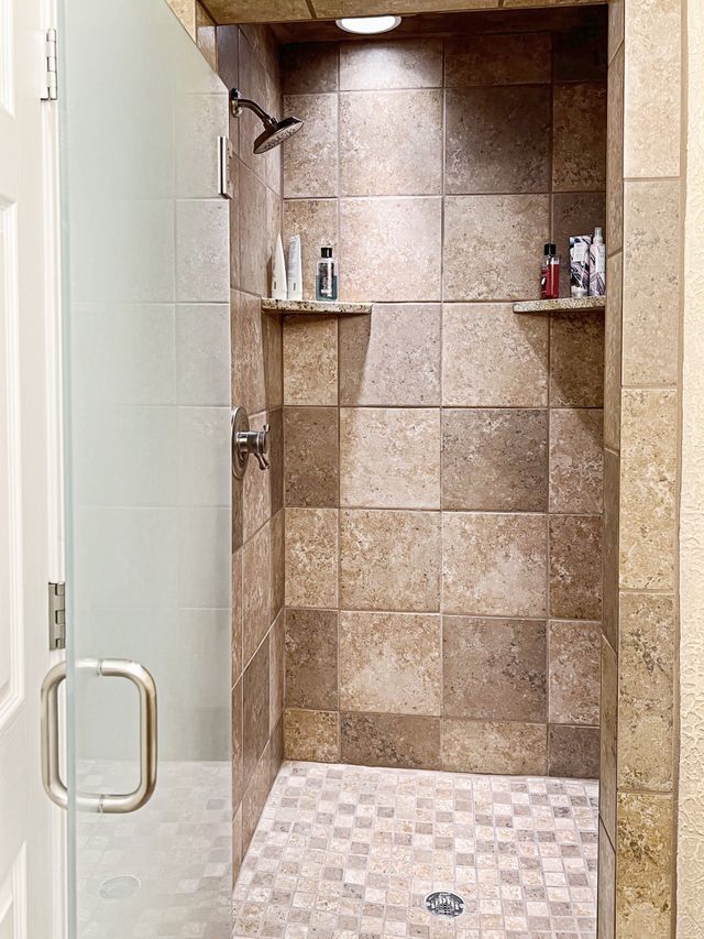 A walk in shower with tiled walls and a glass door