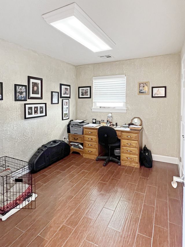 A room with a desk and chair and pictures on the wall