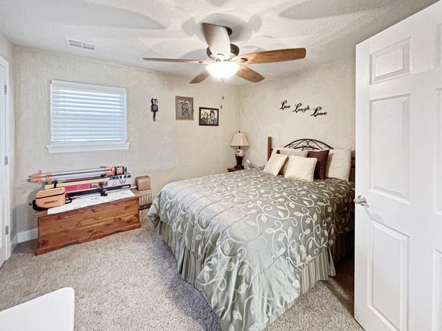 A bedroom with a large bed and a ceiling fan