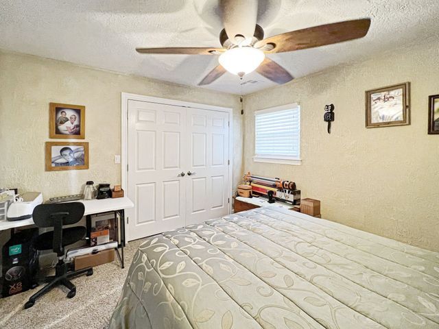 A bedroom with a bed , desk , chair and ceiling fan.