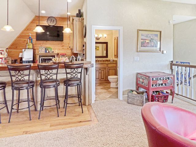 A kitchen with a bar and stools and a pink chair