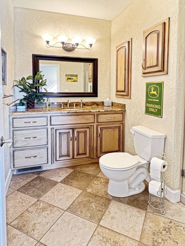 A bathroom with a toilet , sink and mirror.