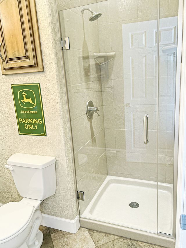 A bathroom with a toilet , shower and sign that says parking only.