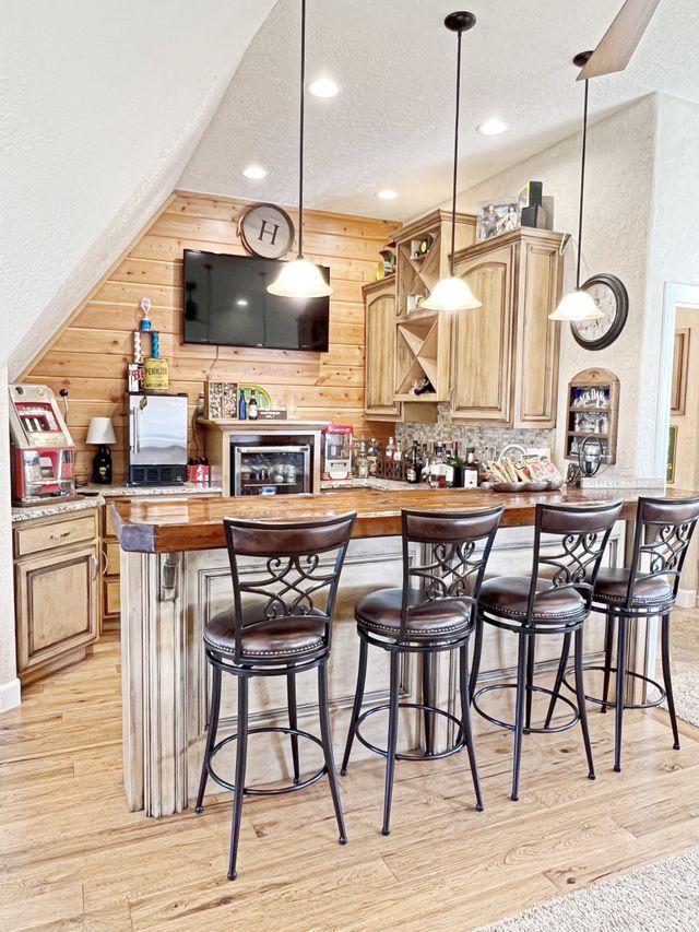 A kitchen with a large island and stools and a flat screen tv on the wall.