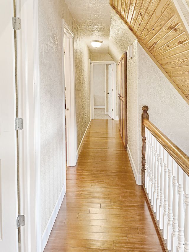 A long hallway with wooden floors and a white railing