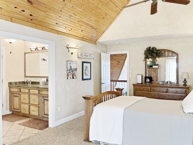 A bedroom with a bed , dresser , mirror and ceiling fan