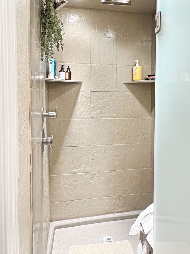 A bathroom with a walk in shower and a glass door.