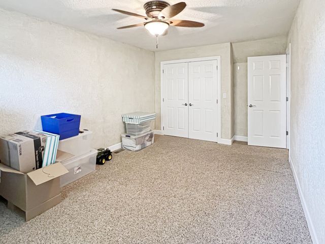 An empty room with boxes and a ceiling fan.