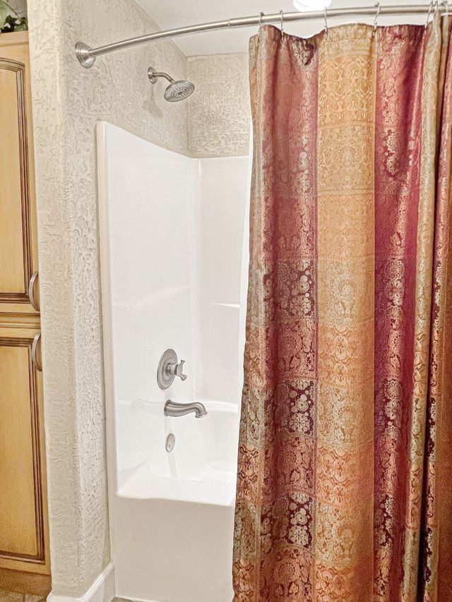 A bathroom with a shower curtain and a bathtub.